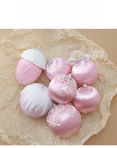 Dettaglio di palline di Natale in raso rosa e paillettes su carta ruvida