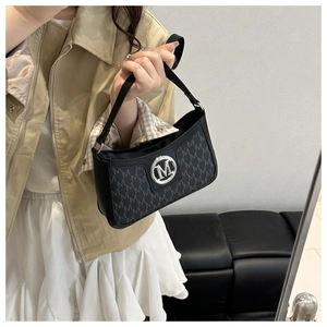 Close-up of black crossbody bag with M monogram print and silver metal logo on model