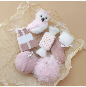 Dettaglio di ornamenti natalizi rosa e bianchi: gufo di peluche, calza e palline