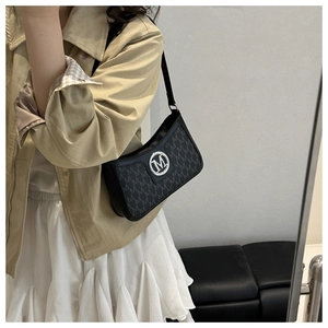 Black monogram crossbody bag with silver M hardware on a model in a minimalist room