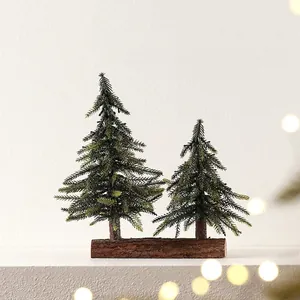 Set of two frosted mini Christmas trees on a natural wooden base for festive tabletop decor