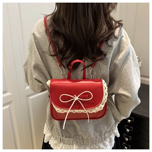 Mini zaino rosso con pizzo bianco e fiocco mostrato sulla schiena di una modella