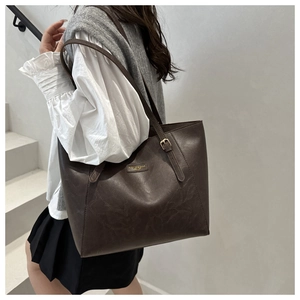 Detailed view of the dark brown retro leather tote bag featuring a gold fashion logo accent