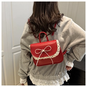 Dettaglio della borsa rossa con bordo in pizzo e fiocco bianco su una modella