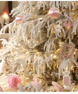 Dettaglio di palline di raso rosa e decorazioni bianche su un albero di Natale con luci LED