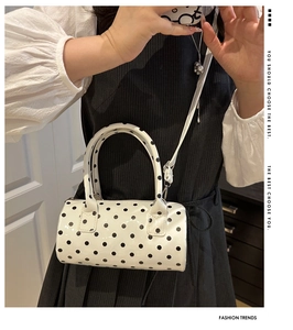 Polished white cylinder bag with black polka dots shown in a mirror selfie style