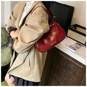 Detail of burgundy glossy underarm bag showing side white text and sleek texture