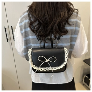Dettaglio mini zaino nero con bordo in pizzo bianco e decorazione a fiocco