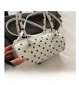 Detailed top view of white polka dot cylinder handbag with silver zipper and shoulder strap