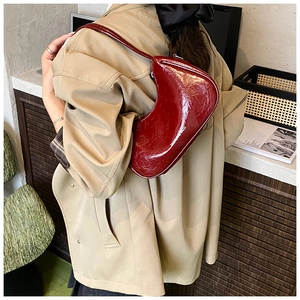 Détail du sac demi-lune bordeaux en cuir verni brillant avec une texture vintage