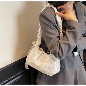 Close-up of elegant white floral lace tote bag with bow detail on female model