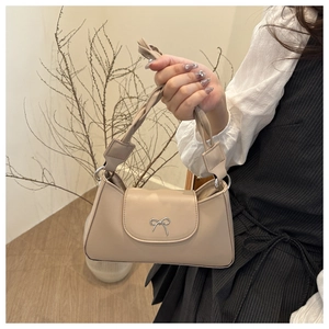 Dettaglio del manico intrecciato e del fiocco argentato sulla borsa beige chic