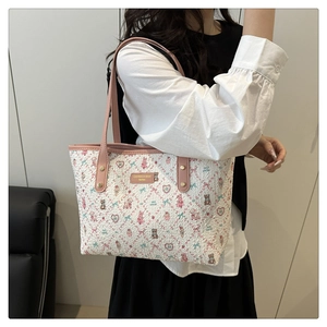 Detail der weißen Web-Tasche mit rosa Bärenmuster und goldenem Logo-Beschlag