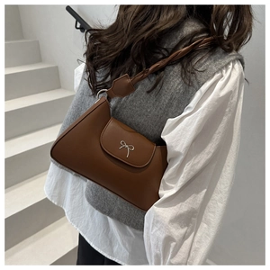 Brown retro underarm bag with metal butterfly and braided shoulder strap on model