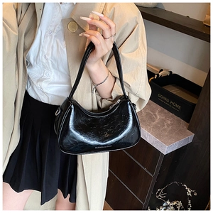 Détail d'un sac sous le bras en cuir plissé noir sur un modèle montrant une forme de croissant