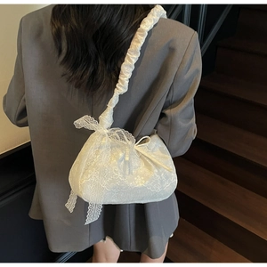 Close-up of elegant white lace tote bag with bow detail on a vintage staircase