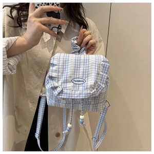Close-up of sky blue plaid backpack with ruffled edges and embroidered fashion logo