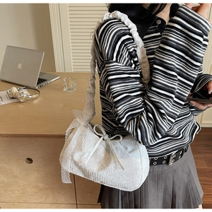Close-up of white lace tote bag with ruffled straps and delicate ribbon bow detail