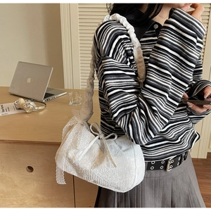 Detail of white floral lace tote bag featuring ruffle shoulder straps and bow drawstring