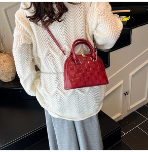 Detail of red embossed patent leather shell bag with gold hardware and shoulder strap