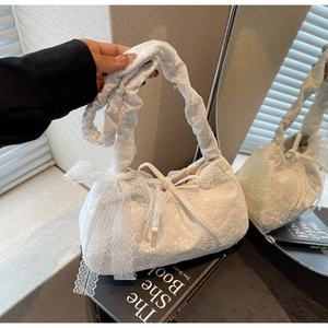 Detail of white floral lace embroidery on a shoulder bag with a decorative ribbon bow