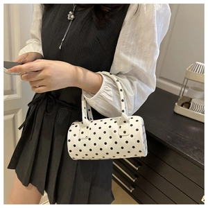 Detailed view of mini polka dot cylinder handbag with double handles and polished finish