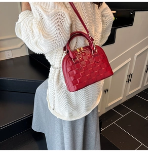 Close-up of red glossy shell bag with embossed lattice texture and golden hardware