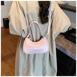 Sac demi-lune rose brillant avec texte mode porté sur un trench-coat beige chic