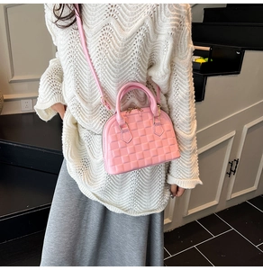 Detailed view of a pink shell handbag with textured quilted pattern on a fashion model