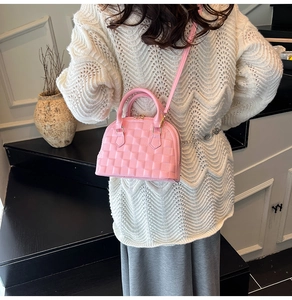Rosafarbene Muschel-Handtasche mit Gitterprägung getragen zu einem weißen Strickpullover
