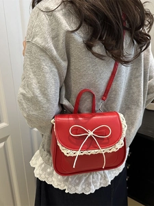 Borsa a tracolla in pelle PU rossa con pizzo e fiocco su sfondo di porta bianca
