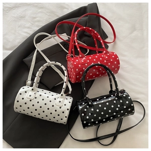 Detailed top view of three polka dot cylinder bags in white, red, and black on a grey suit