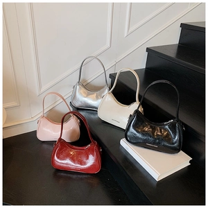 Five glossy crinkled leather underarm bags in various colors on black steps