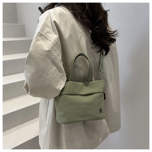 Detail of light green bucket bag showing high-density canvas texture and metal logo