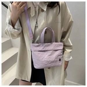 Detalle de mini bolso tote lavanda con textura plisada y correa de tela ajustable