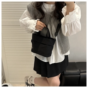 Detail of black mini bucket bag showing removable strap and nylon texture for daily use