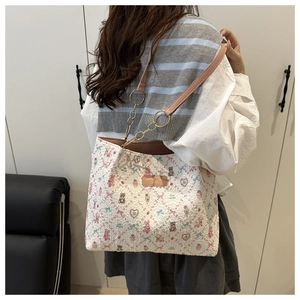 Detail of floral tote bag with cartoon bear print and golden metal chain strap