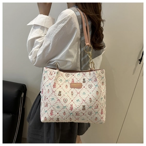 Close-up of quilted white tote bag featuring pink bear prints and golden chain hardware