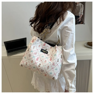 Detail shot of a white floral tote bag with cute animal patterns and gold chain strap