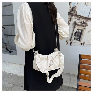 Close-up of white ruched shoulder bag featuring pearl strap and metal chain detail