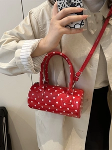 Mini red polka dot barrel bag with adjustable strap and top handles for crossbody wear