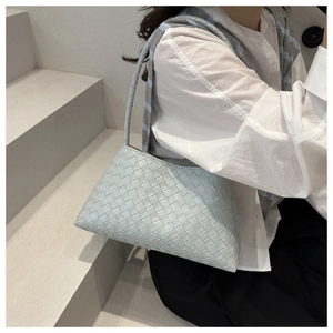 Detail of light blue woven texture shoulder bag worn by model on minimalist steps