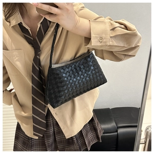 Close-up of black leather woven texture on a stylish baguette bag with shoulder strap
