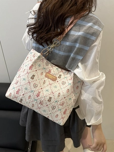 Floral print tote bag with cute bear patterns and metal chain strap worn by a model