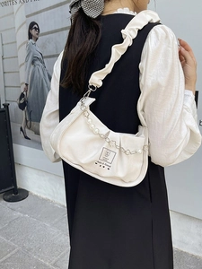Chic white pleated crossbody bag with faux pearl and flower chain detail on urban background