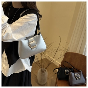 Detail of silver underarm bag with gold buckle on a model in a retro setting