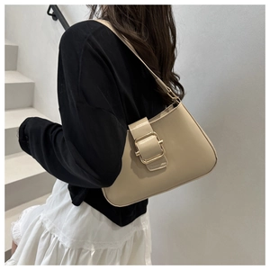 Detail of minimalist beige leather crossbody bag with a large gold metal buckle on a model