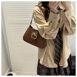 Detail of vintage brown underarm bag with gold metal buckle on preppy style outfit