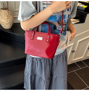 Vue détaillée du sac seau rouge brillant avec clous argentés et texture à effet miroir poli