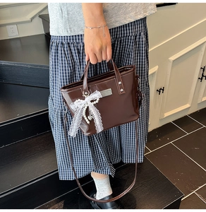Détails du sac seau en cuir verni marron foncé avec nœud en dentelle blanche et perles